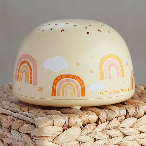 A little lovely company beige nachtlamp en sterprojector met regenboog- en sterpatronen op een gevlochten ondergrond.