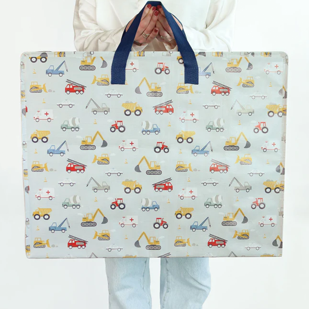 Een persoon houdt de a little lovely company XL opbergtas met voertuigenpatroon vast, frontaal gefotografeerd.