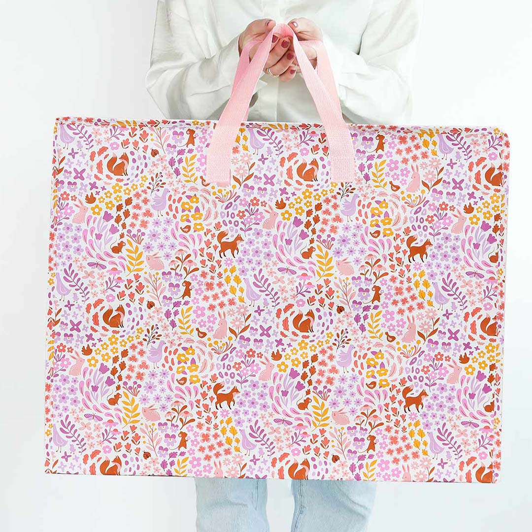 Een persoon toont de a little lovely company opbergtas met bloemen- en dierenpatroon.
