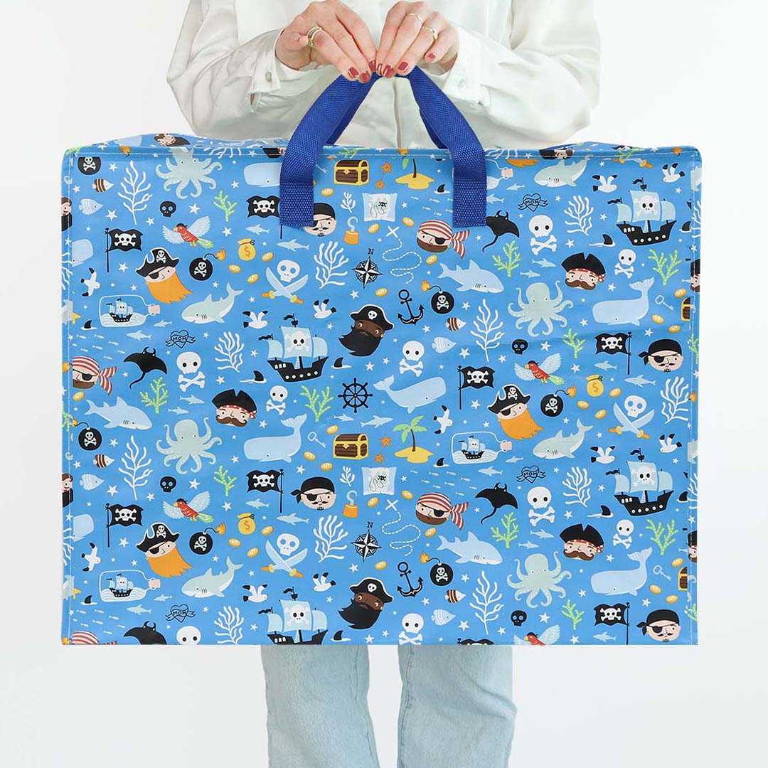 Een persoon houdt de a little lovely company XL opbergtas met piratenprint vast, gezien vanaf de voorkant.