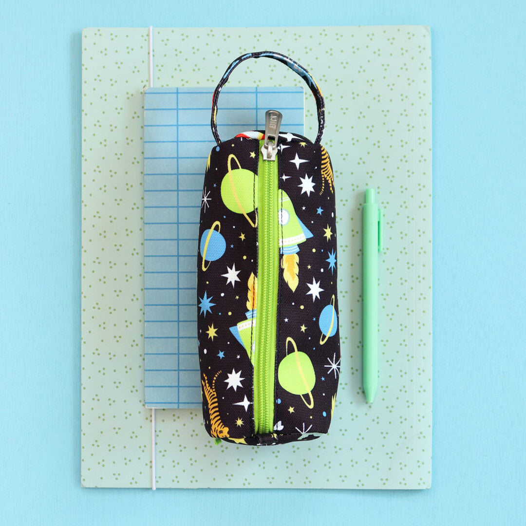 a little lovely company pennenetui met galaxy-thema, van bovenaf gefotografeerd naast een groene pen.