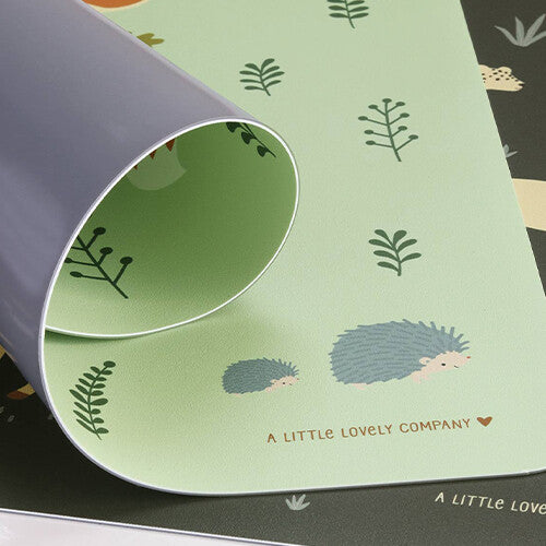 Detail van de A little lovely company placemat met bosdieren, waarbij een hoek is opgerold en de grijze onderkant zichtbaar is.