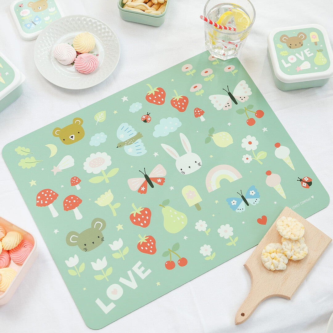 De groene a little lovely company placemat met dieren- en bloemenpatroon ligt op een tafel met snacks en drinken.