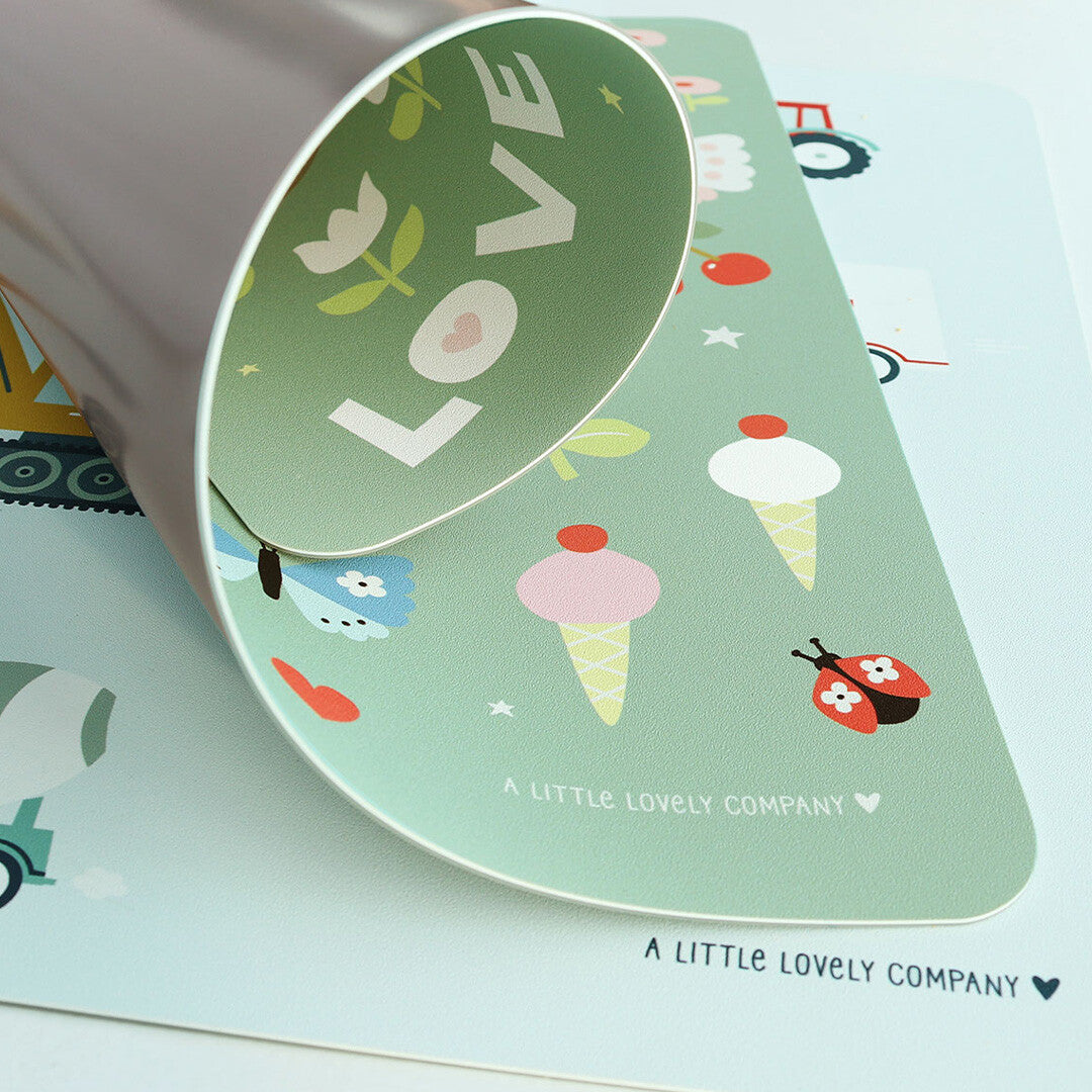 Detail van de groene a little lovely company placemat met dieren- en bloemenpatroon, waarbij een hoek is opgetild.