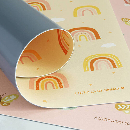 Detailfoto van de a little lovely company placemat met regenbogen en sterren, deels opgerold om de grijze onderkant te tonen.