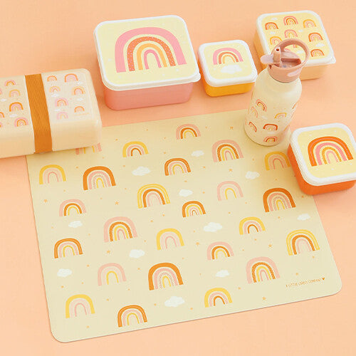 A little lovely company placemat met regenbogen en sterren, omringd door bijpassende lunchboxen en een drinkfles.
