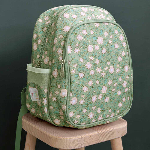 A little lovely company groene schoolrugzak met bloemenpatroon op een houten krukje.