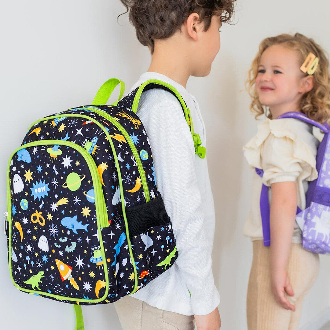 Jongen draagt de a little lovely company schoolrugzak met galaxy-thema, staand naast een meisje.