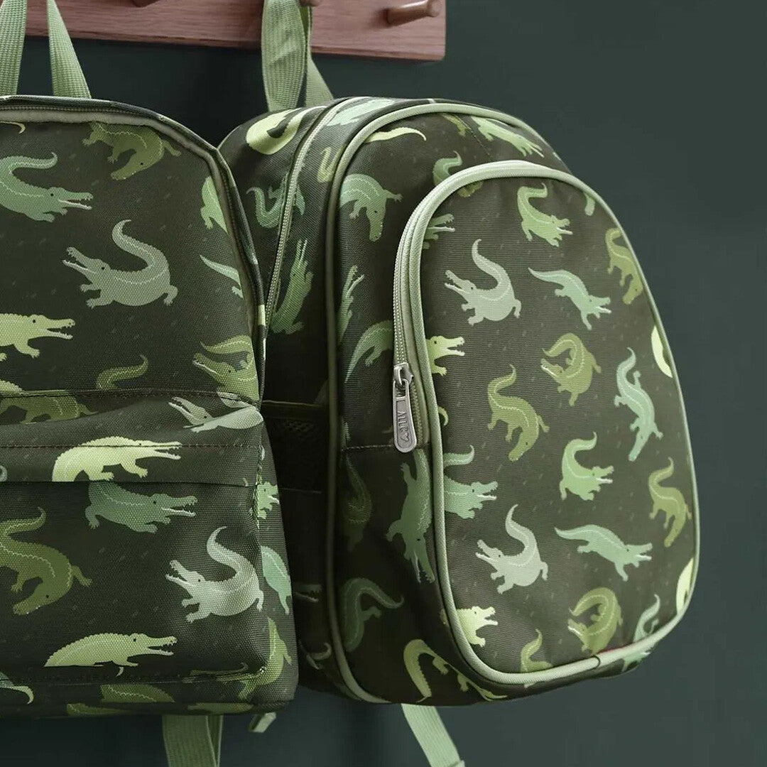 Twee a little lovely company groene schoolrugzakken met krokodillenpatroon hangen aan een houten kapstok.