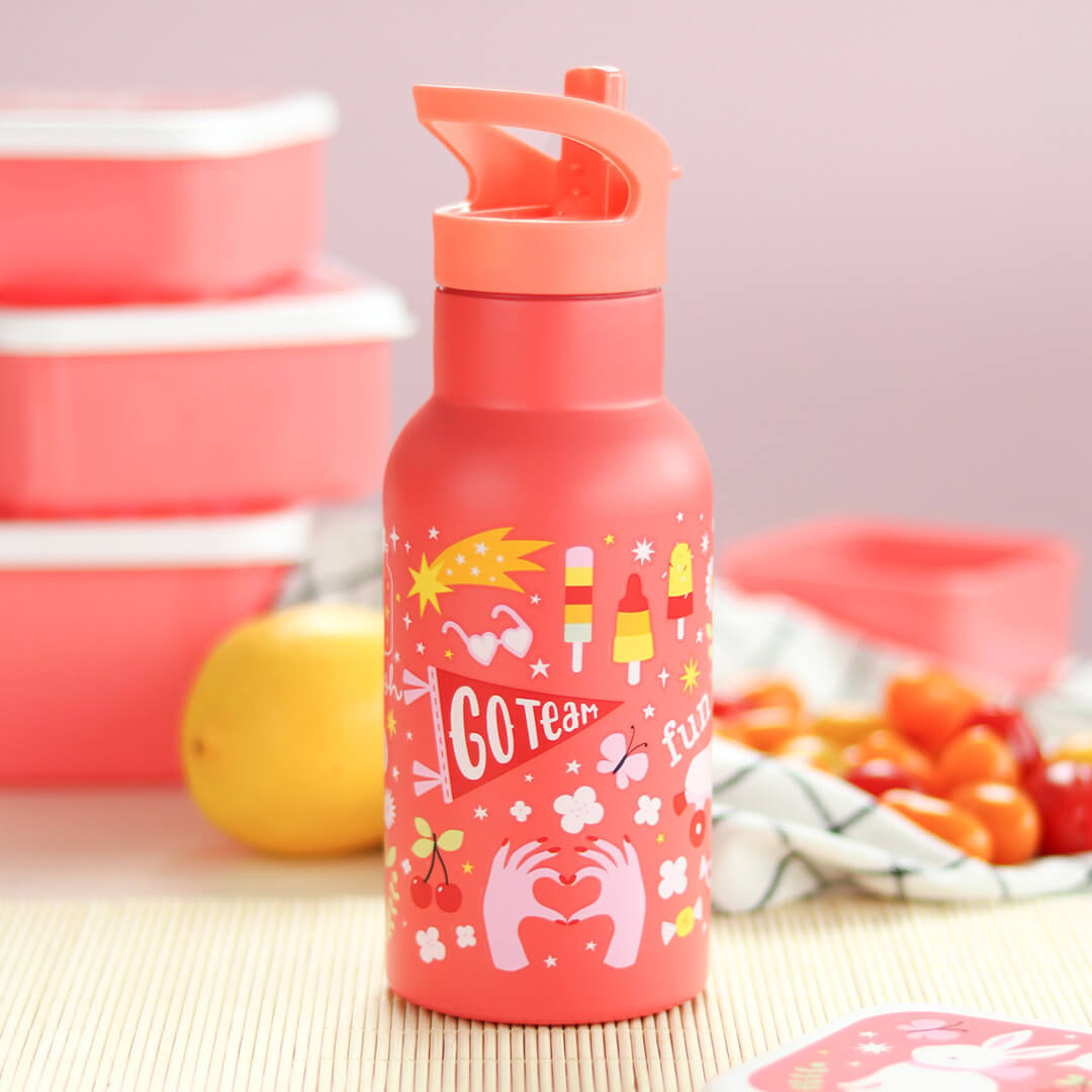 Roze a little lovely company kinderdrinkfles met illustraties van ijsjes en een spandoek, staand op een mat met lunchboxen en fruit.