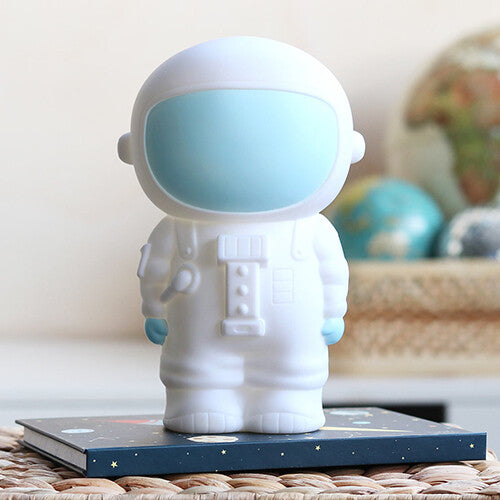Witte astronaut spaarpot op een donkerblauw boek met sterren.