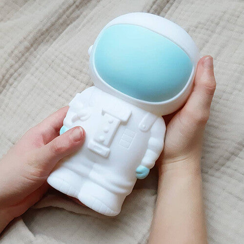 Twee handen houden de witte astronaut spaarpot vast.