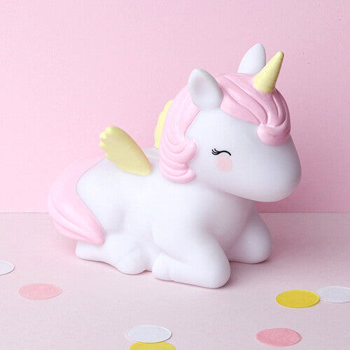 Witte eenhoorn spaarpot van a little lovely company op een roze ondergrond met confetti.