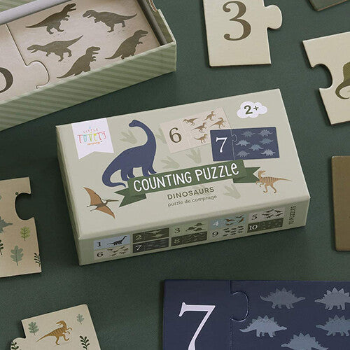 Close-up van de a little lovely company telpuzzel doos met dinosaurussen, omringd door enkele puzzelstukken.