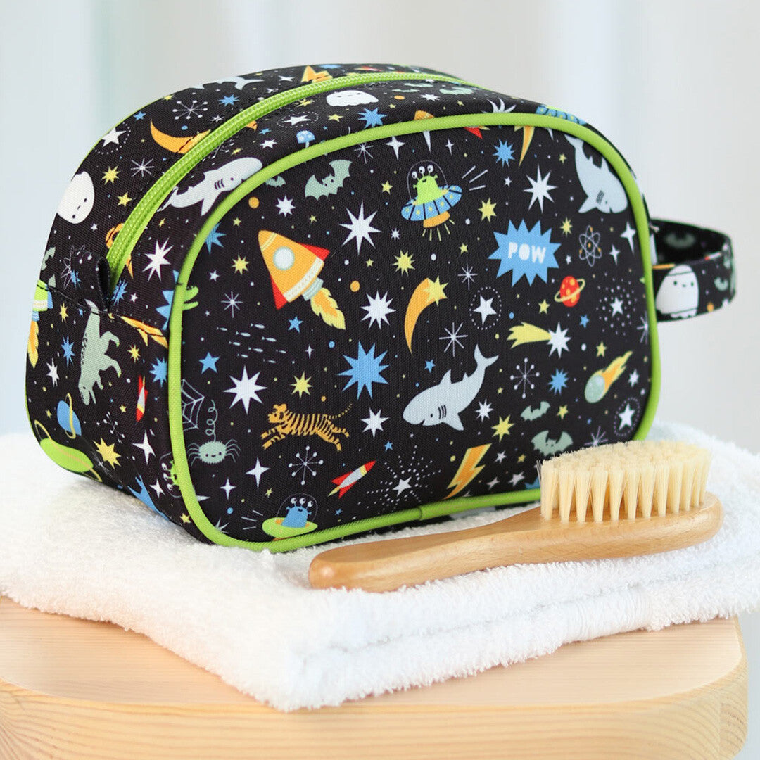 a little lovely company toilettas met galaxy-thema op een witte handdoek naast een houten borstel.