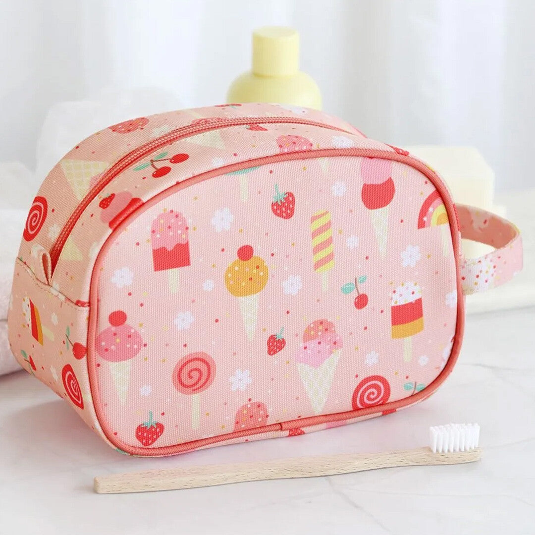 A little lovely company roze toilettas met ijsjes patroon op een badkamerplank naast een tandenborstel.