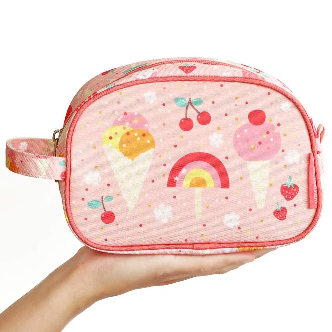 Een hand houdt de a little lovely company roze toilettas met ijsjes patroon vast voor schaal.