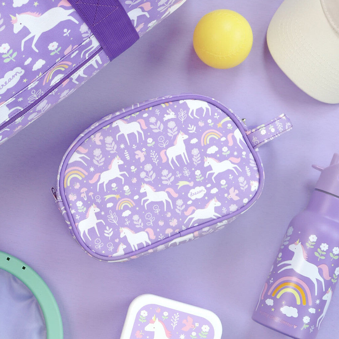 a little lovely company toilettas met eenhoornpatroon, liggend tussen bijpassende items op een paarse ondergrond.