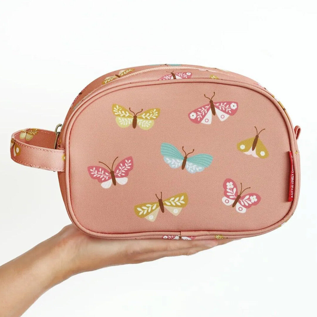 Een hand houdt de roze toilettas met vlinders vast om de grootte te tonen.