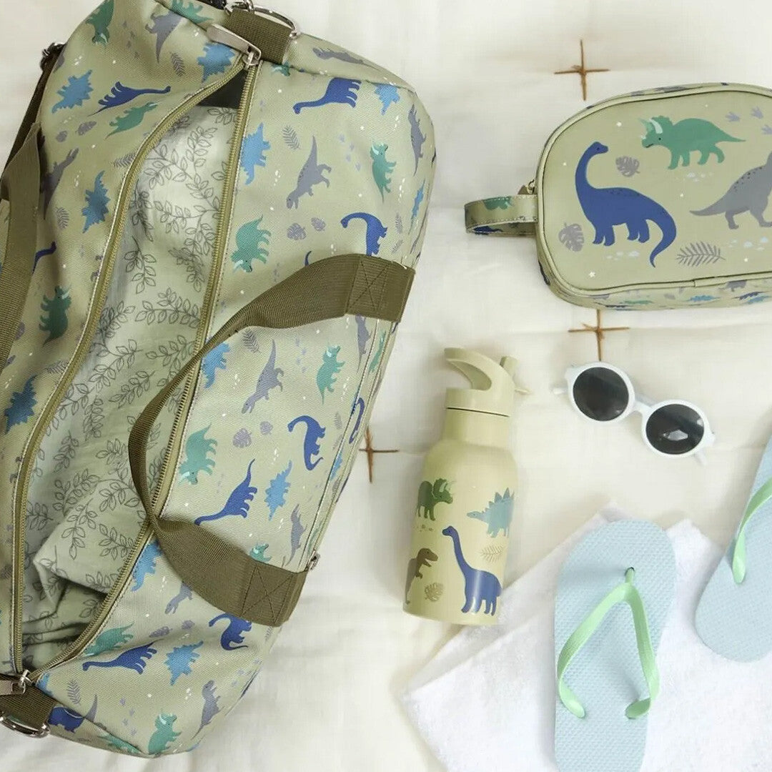a little lovely company groene kinderweekendtas met dinosauruspatroon naast bijpassende reisaccessoires.