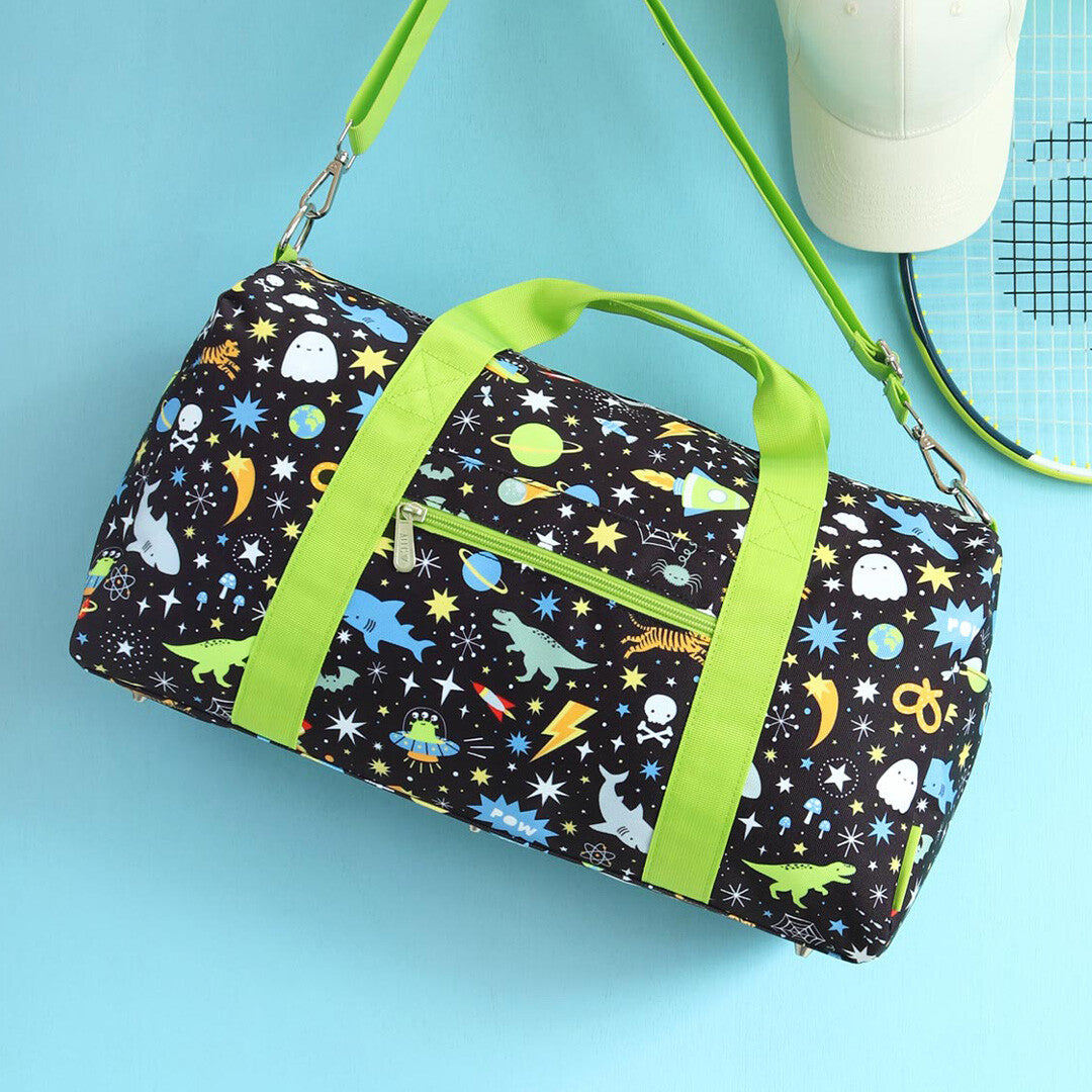 De a little lovely company kinder weekendtas met galaxy patroon en groene schouderband ligt op een blauwe ondergrond.