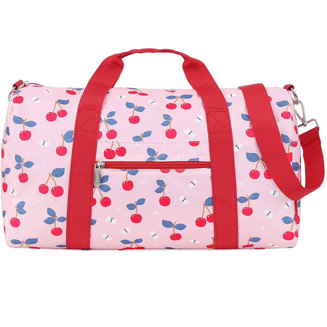 Een roze a little lovely company kinder weekendtas met kersenprint en rode hengsels, van voren gefotografeerd op een witte achtergrond.