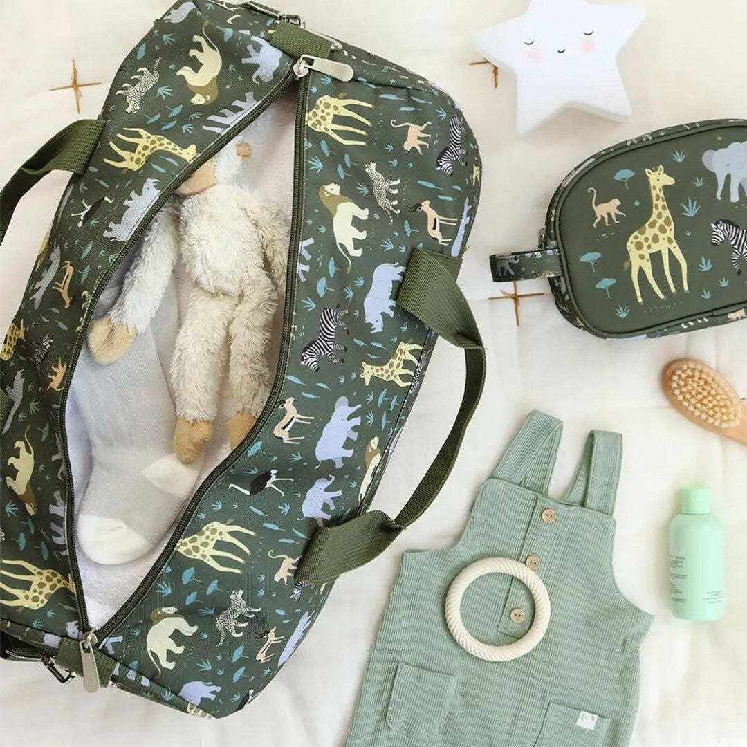 Een open a little lovely company groene kinderweekendtas met savannedierenpatroon, gevuld met een knuffel, ligt naast een bijpassende toilettas en babykleding.