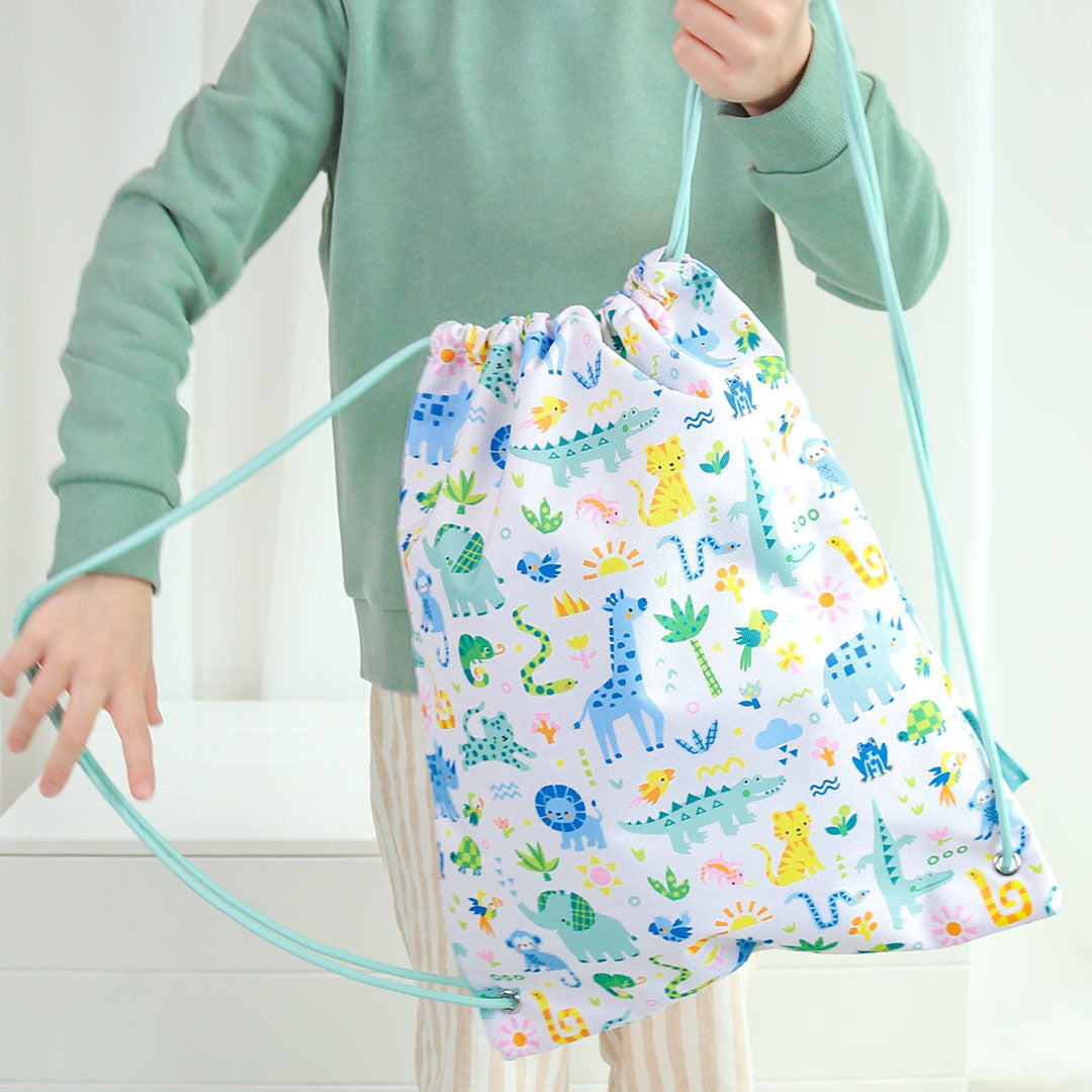 Kind draagt een gymtas met jungle dierenprint over de schouder.
