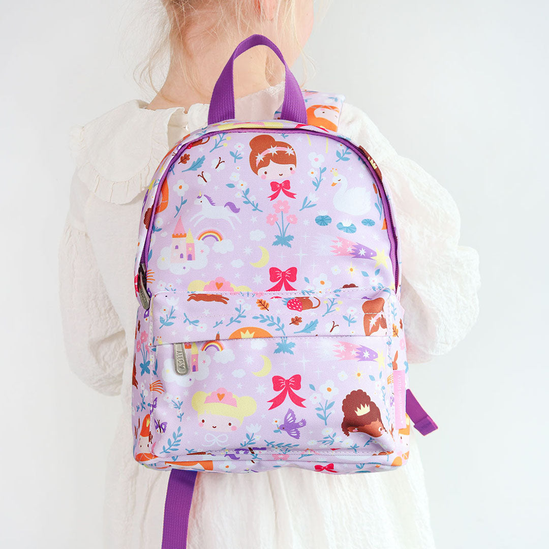 Een kind draagt de a little lovely company kleuterrugzak met prinsessenpatroon op de rug.