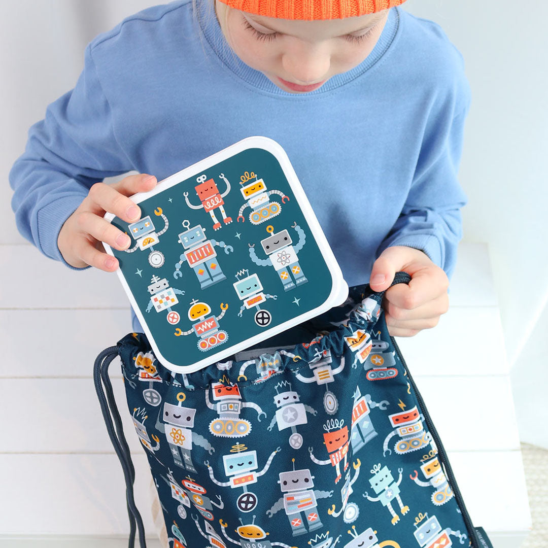 Een kind stopt een a little lovely company lunchbox met robotprint in een bijpassende rugzak.