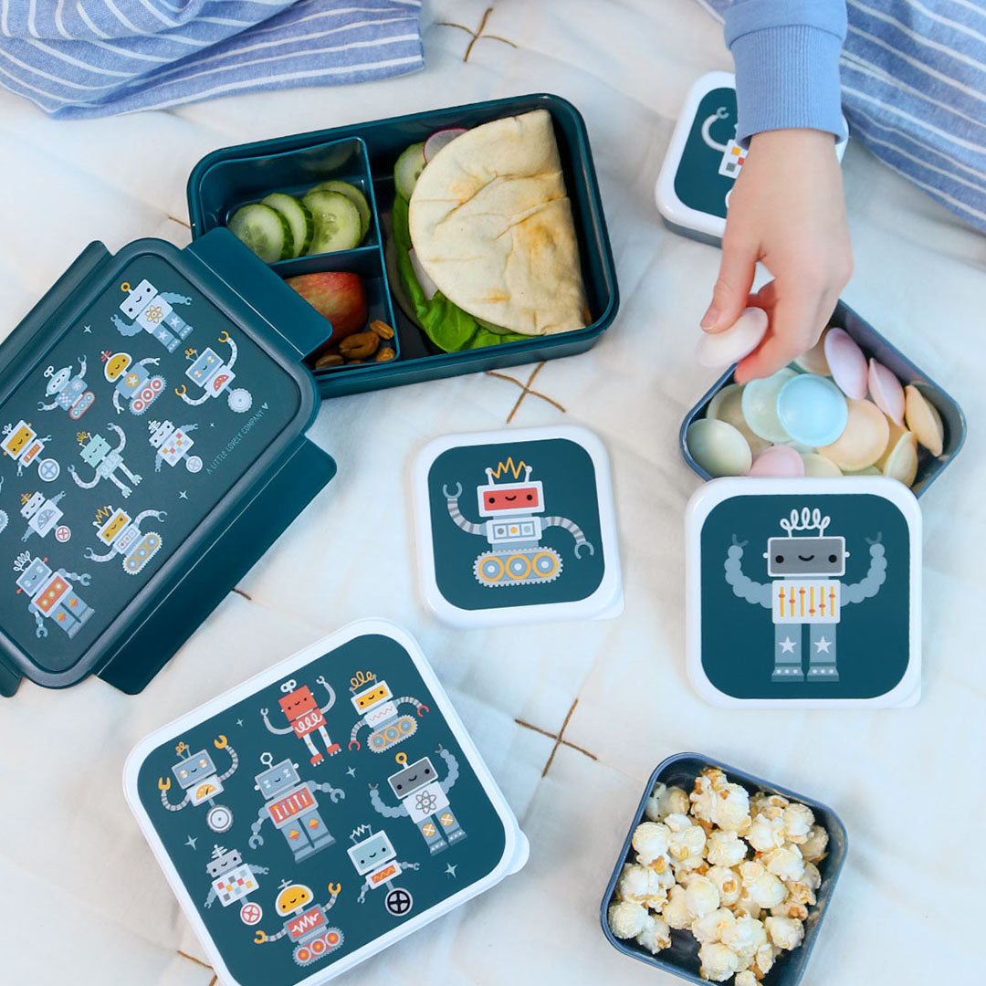 Diverse a little lovely company robot lunchboxen en snackboxen voor kinderen gevuld met eten op een deken.