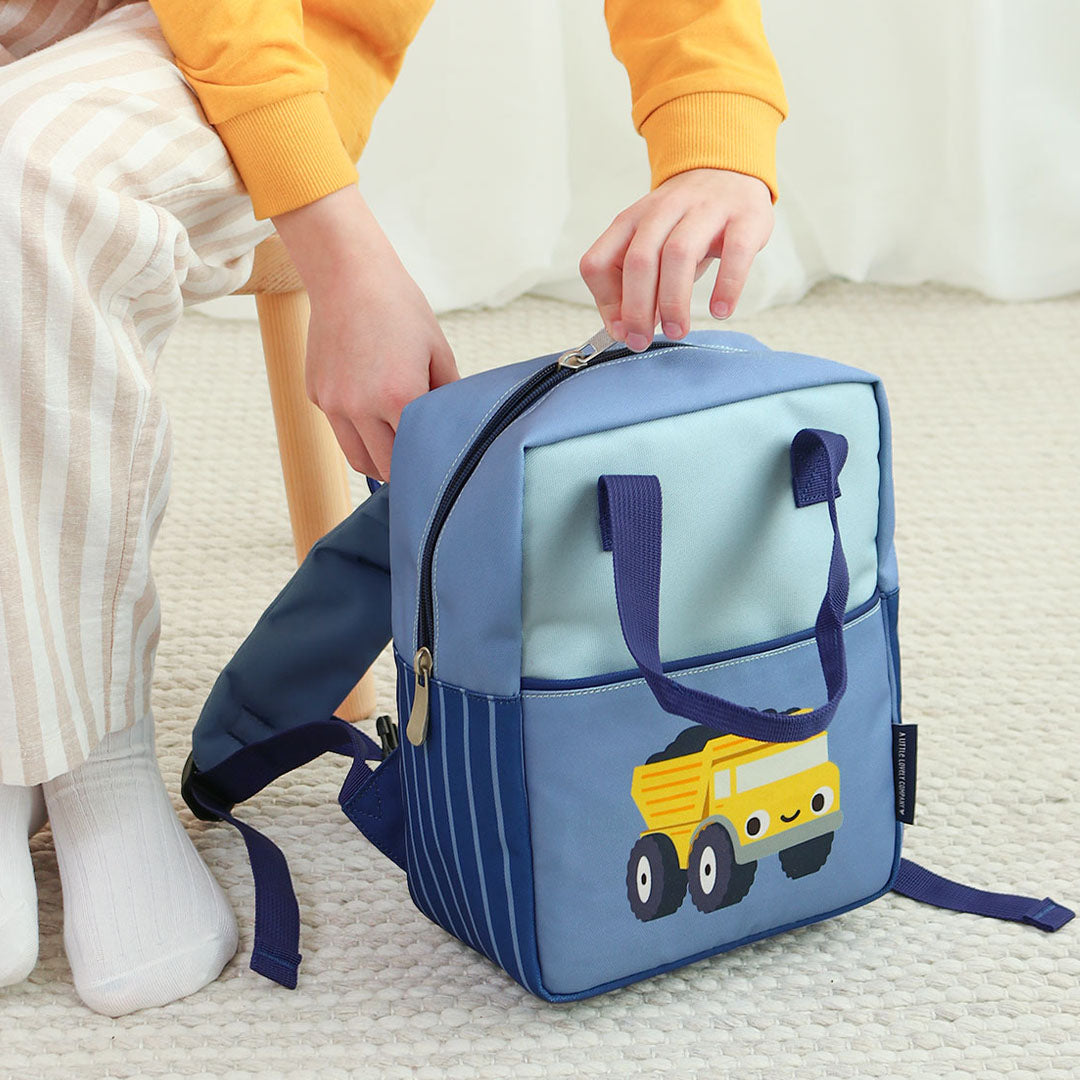 Een kind opent de rits van de a little lovely company peuterrugzak met kiepwagen-illustratie.