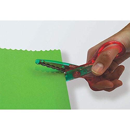 Een hand knipt met een rode kartelschaar een golvende rand in groen papier.