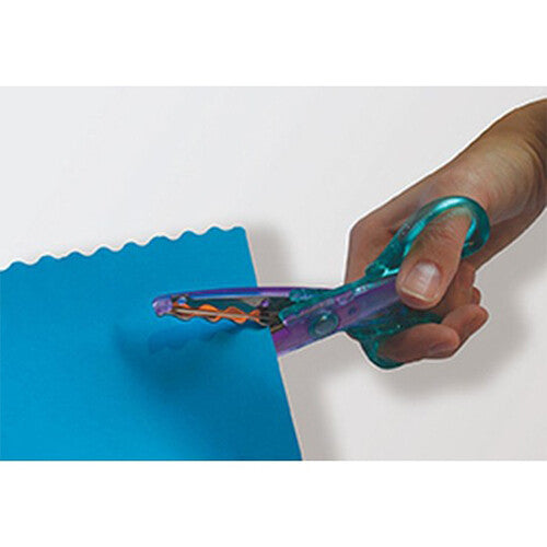 Een hand knipt met een blauwe kartelschaar een golvende rand in blauw papier.