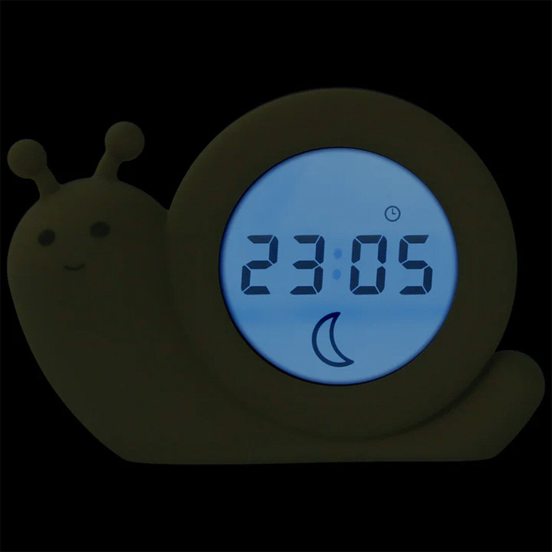 Zazu slaaptrainer en wekker in de vorm van een slak in het donker, met een blauw verlicht display dat 23:05 en een maan toont.