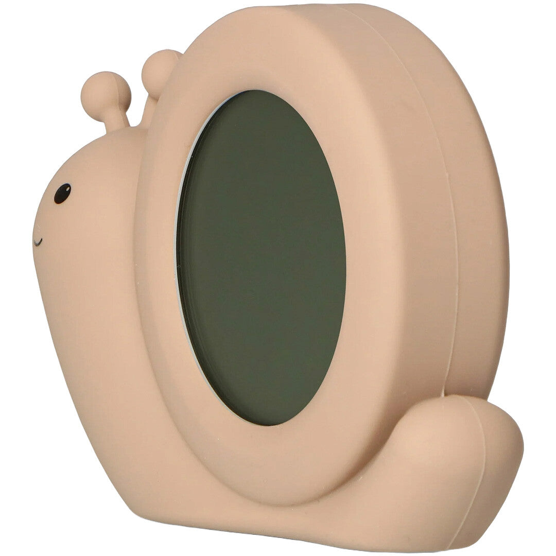 Zazu slaaptrainer en wekker in de vorm van een beige slak, schuin van de zijkant gezien met een donker display.