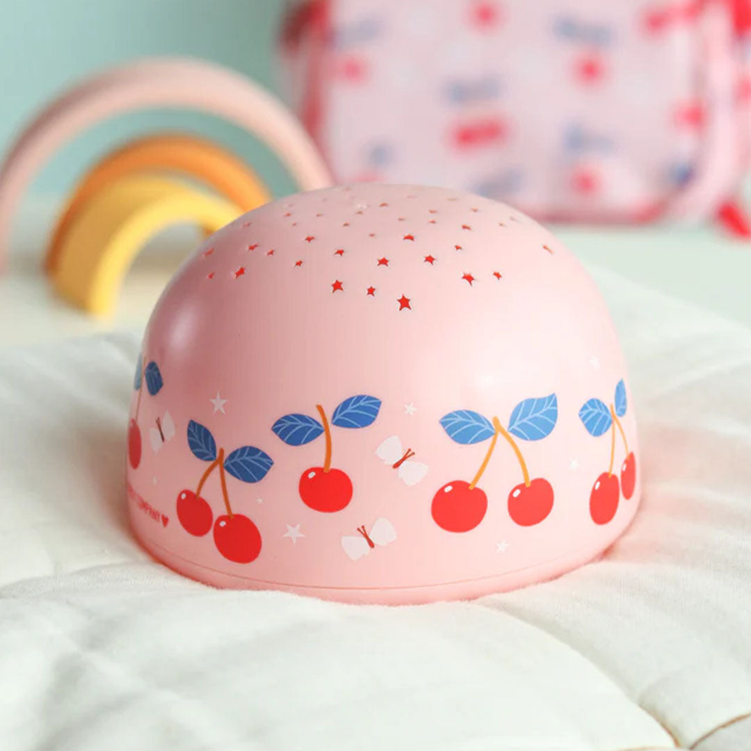 De A Little Lovely Company roze nachtlamp en sterprojector met kersenpatroon op een witte ondergrond.