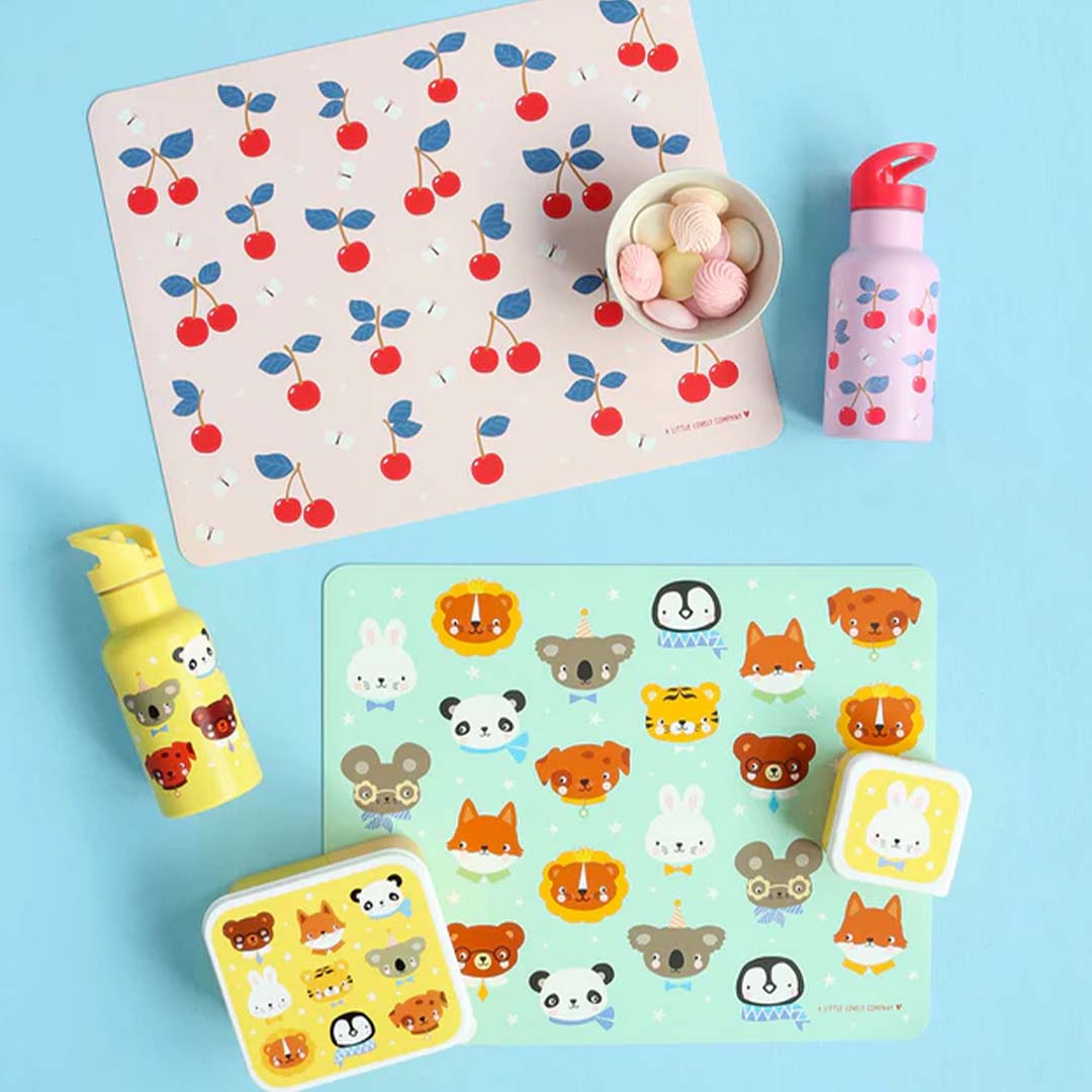 Twee A Little Lovely Company placemats, één met dierenvriendjes en één met kersen, met bijpassende accessoires.