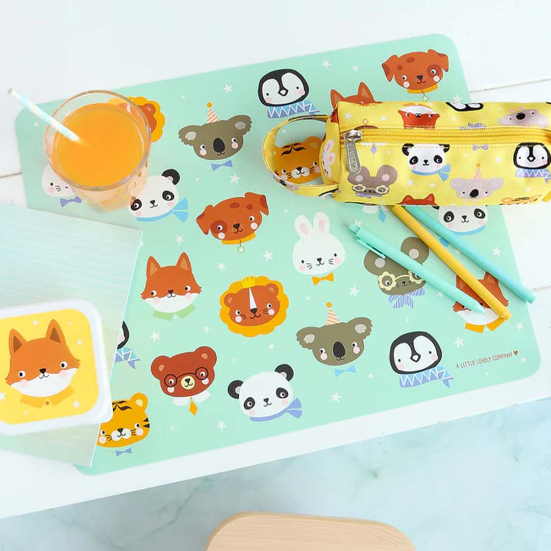 Een A Little Lovely Company placemat met dierenvriendjes op tafel met een glas sap en een etui.