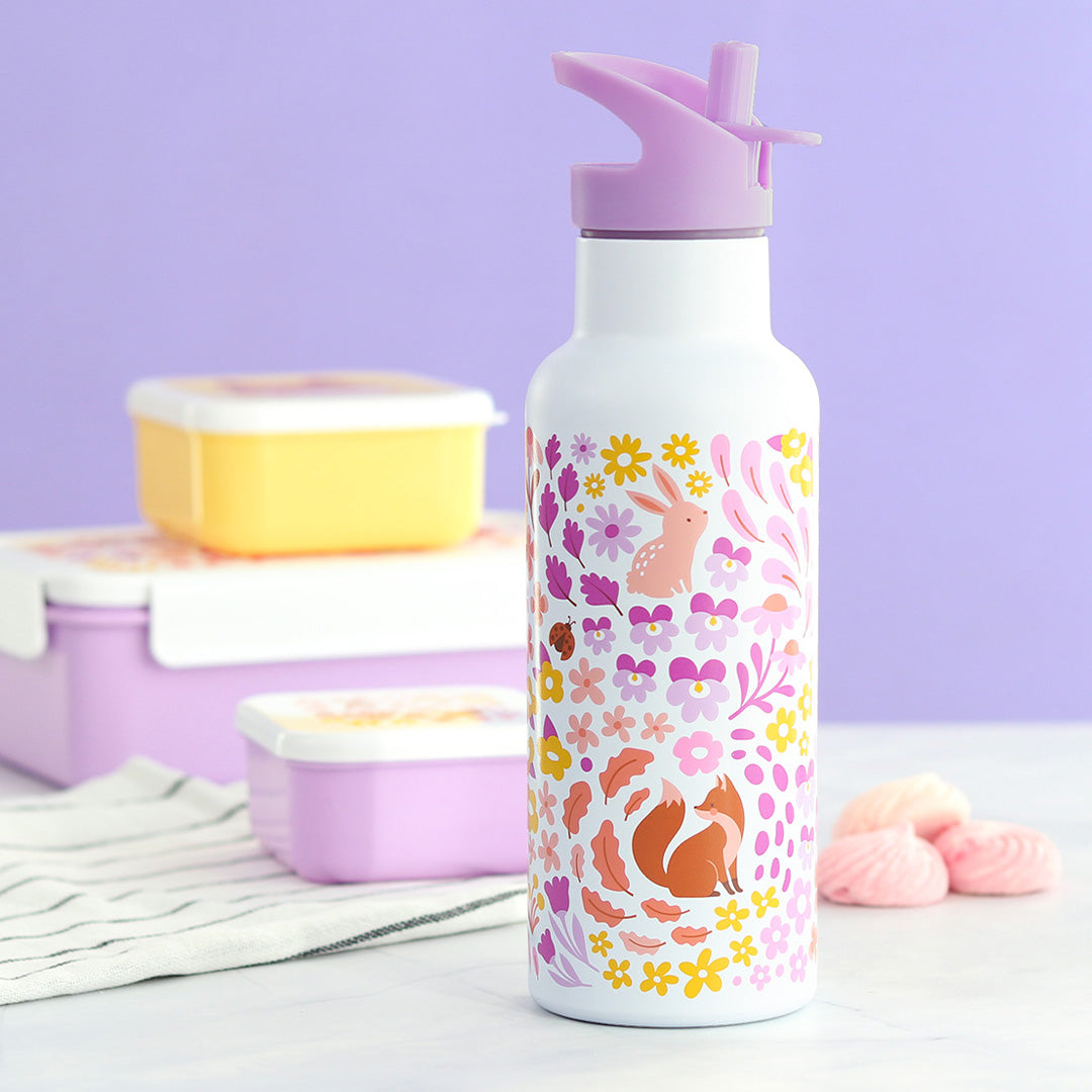 A little lovely company rvs kinderdrinkfles met bloemen- en dierenpatroon, staand tussen lunchboxen en marshmallows.