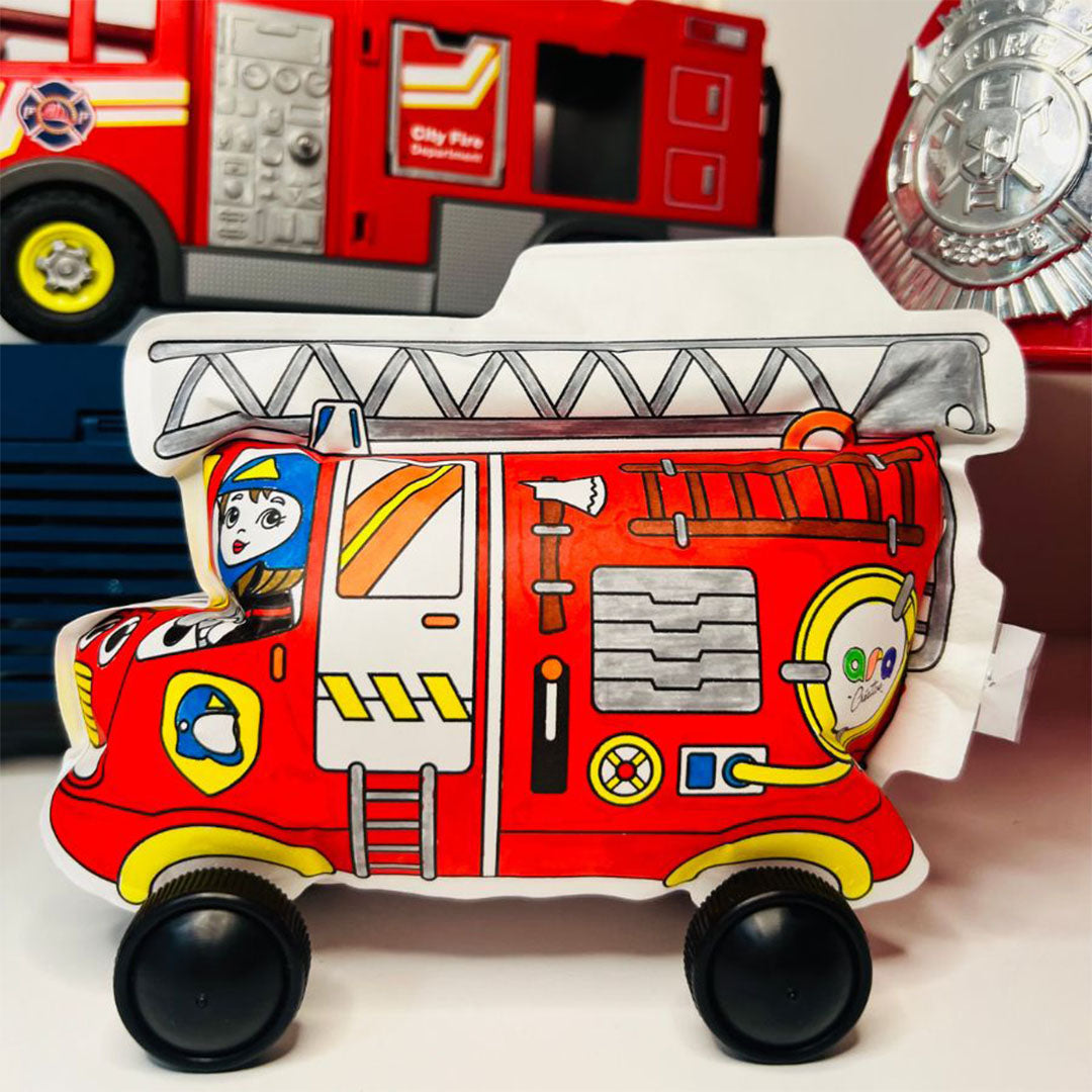 De gekleurde, opblaasbare brandweerwagen staat op een ondergrond met andere speelgoedvoertuigen op de achtergrond.