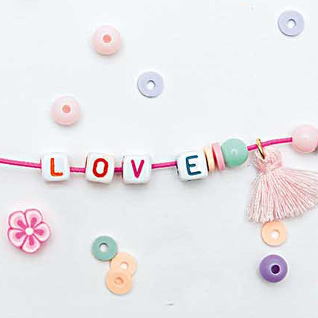 Losse kralen, letterkralen, bloemetjes en een roze kwastje van de Rico Design sieraden maken set.