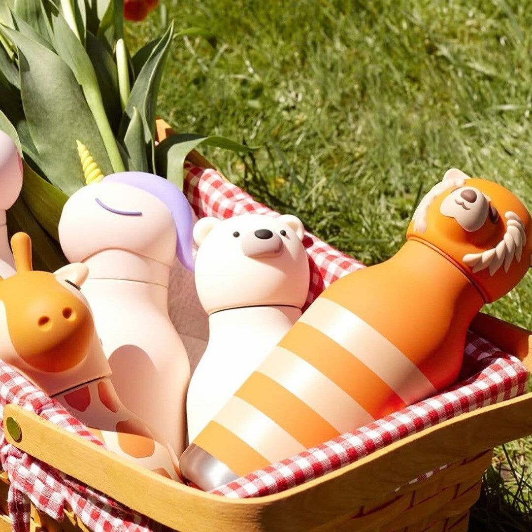Vier asobu rvs drinkflessen met dierenfiguren, waaronder een beer, in een picknickmand.