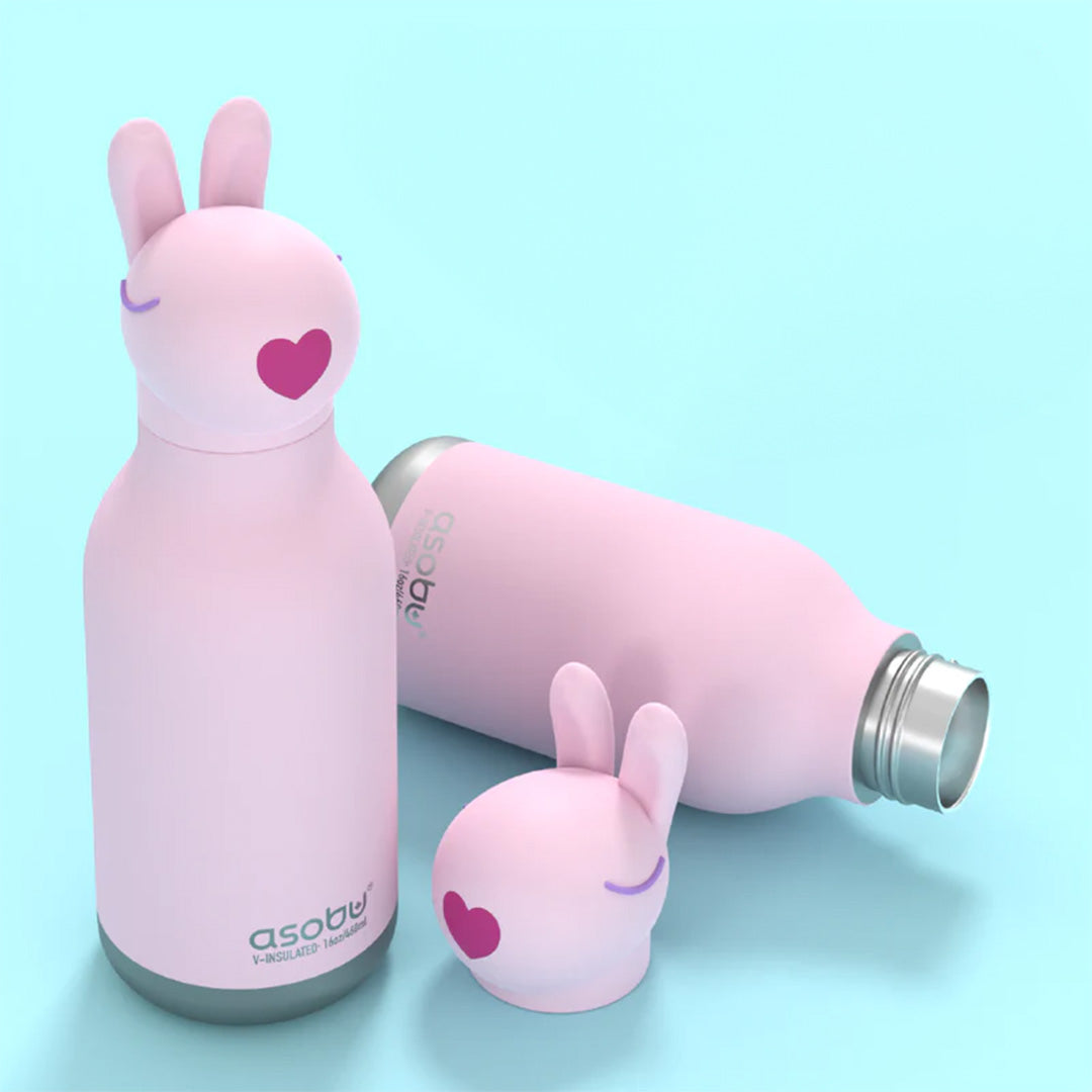 Twee roze asobu konijn drinkflessen, waarvan één liggend, met een losse konijnenkop dop op een blauwe ondergrond.