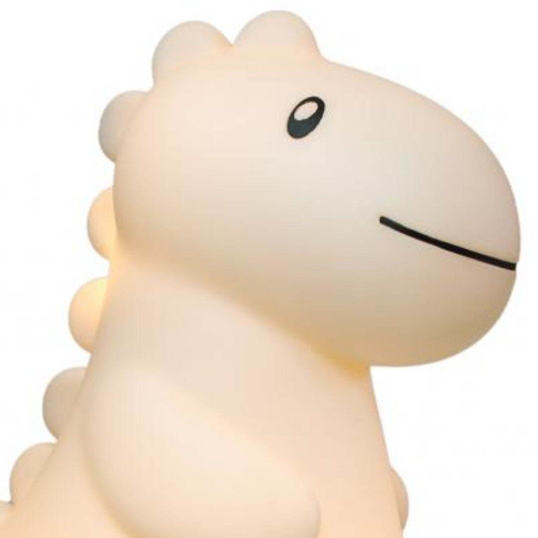Close-up van de zandkleurige dino kinderlamp met een vriendelijke glimlach.