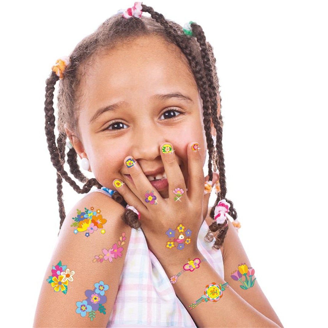 Een lachend meisje toont Avenir nagelstickers op haar nagels en bloementattoos op haar arm en hand.