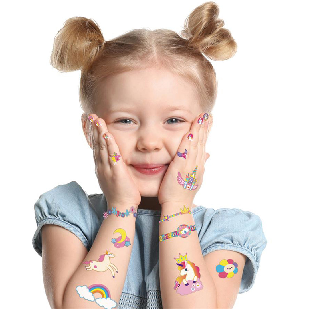 Een lachend meisje met eenhoorn nagelstickers en tattoos op haar handen en armen.