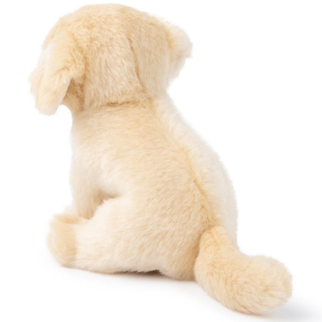 De achterkant van de pluchen labrador puppy knuffelhond, zittend.