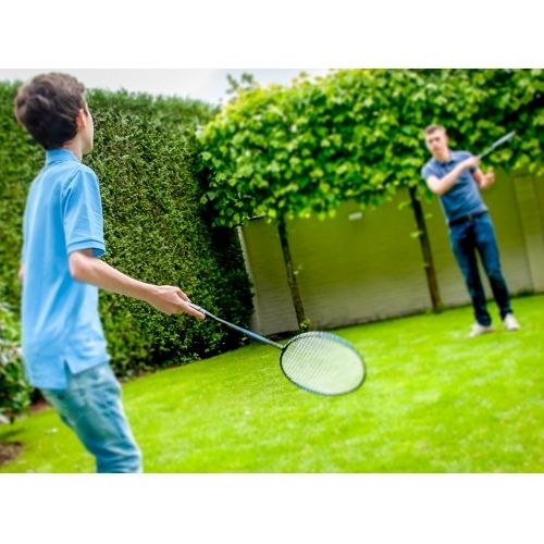 Twee jongens spelen badminton met blauwe rackets in een groene tuin.