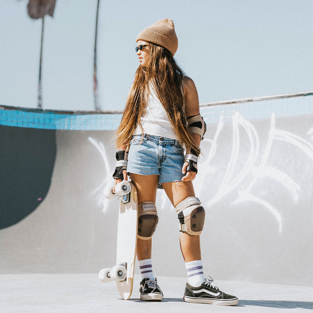 Een kind staat in een skatepark met de Banwood beschermingsset aan en een skateboard in de hand.